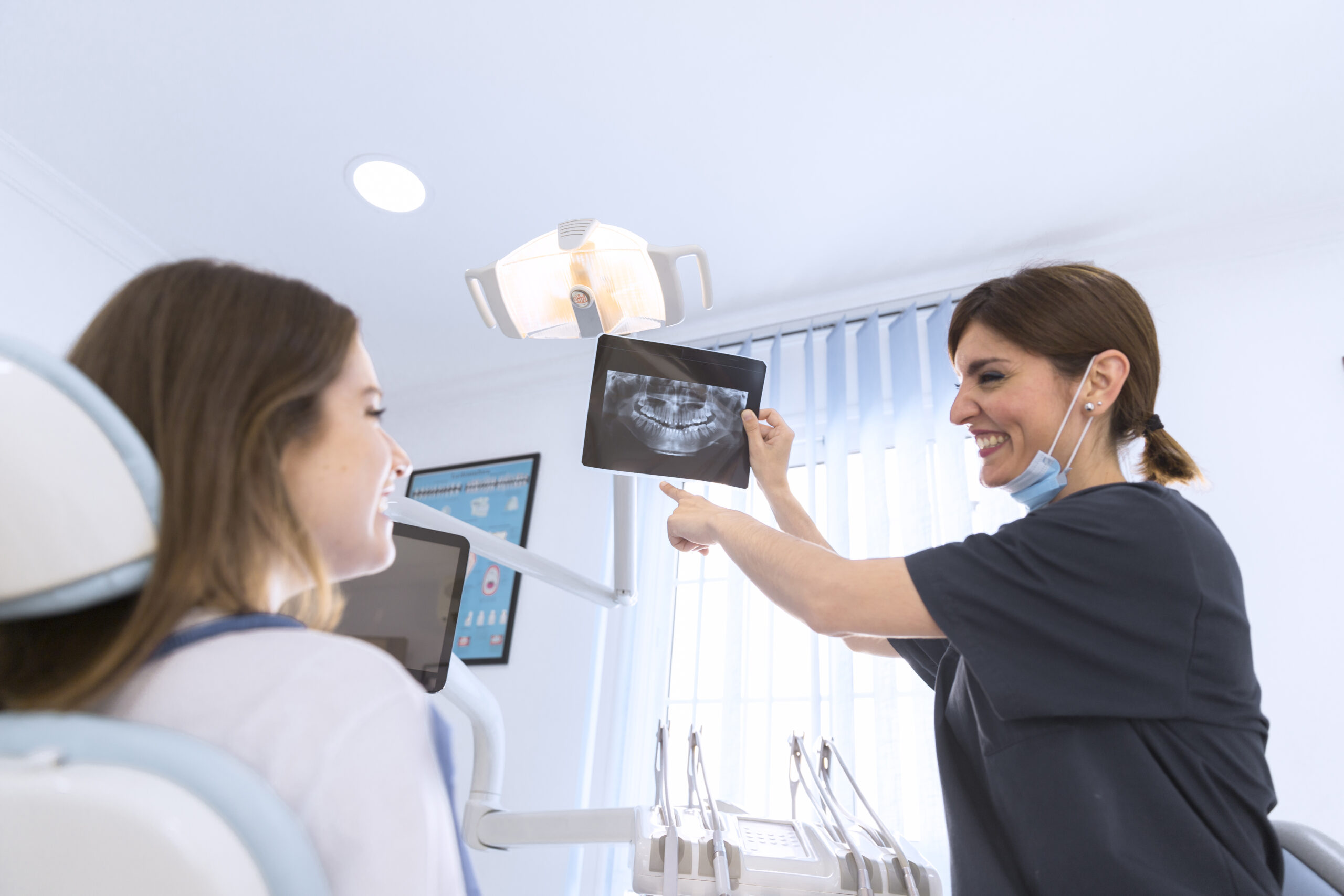 happy-smiling-female-dentist-showing-dental-x-ray-to-patient